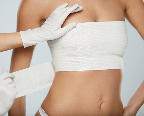 Plastic Surgery. Doctor Hands Wrapping Female Breast In Bandage