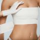 Plastic Surgery. Doctor Hands Wrapping Female Breast In Bandage