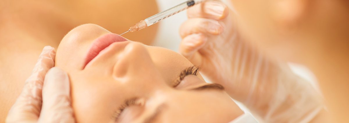 Cosmetology doctor makes beauty injections in the lip to a woman.