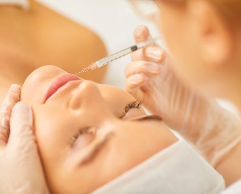 Cosmetology doctor makes beauty injections in the lip to a woman.