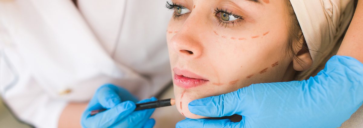 Doctor drawing marks on female face